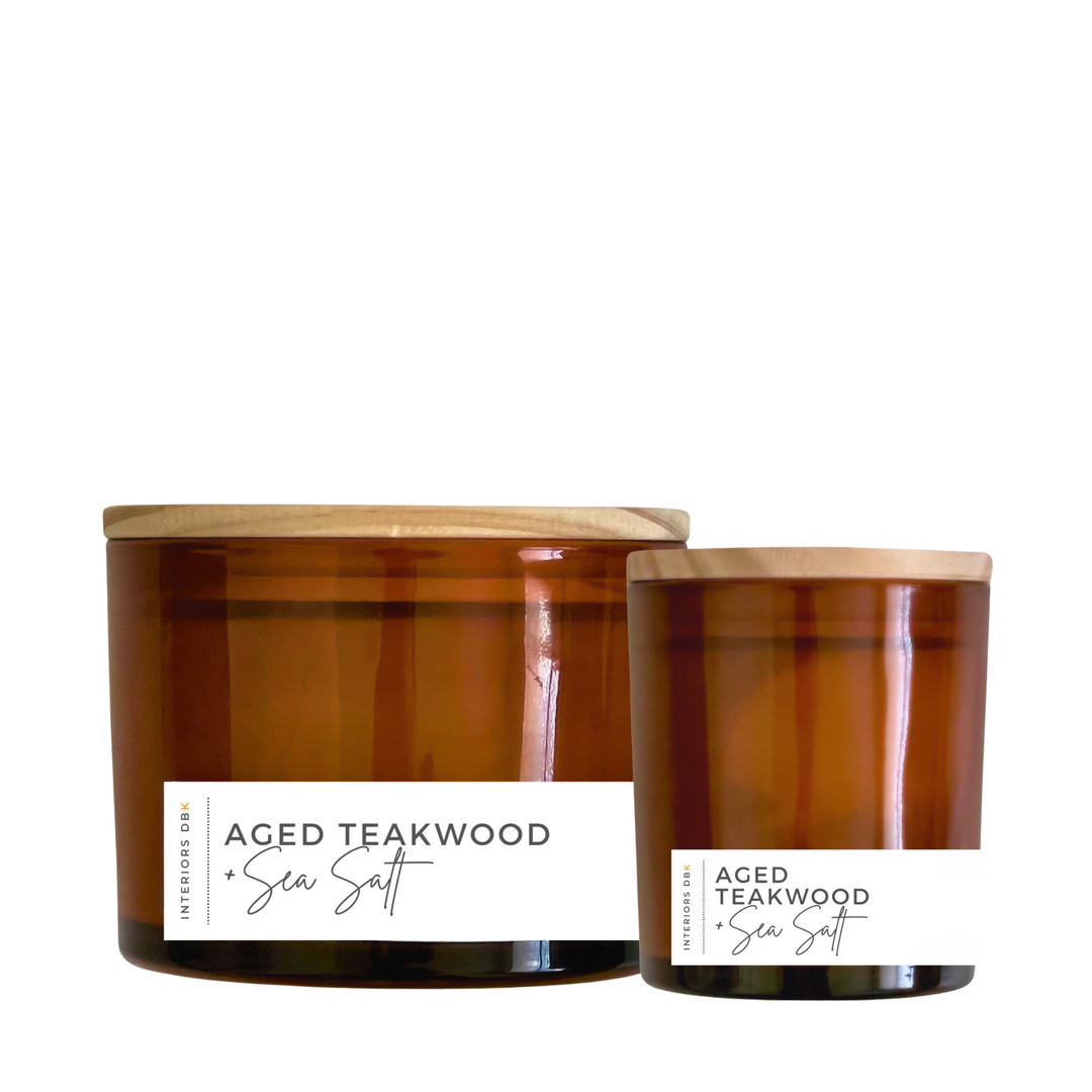 A set of Aged Teakwood & Sea Salt soy candles in amber glass vessels, featuring a small and large candle with natural wood lids, showcasing the elegant and sustainable design.