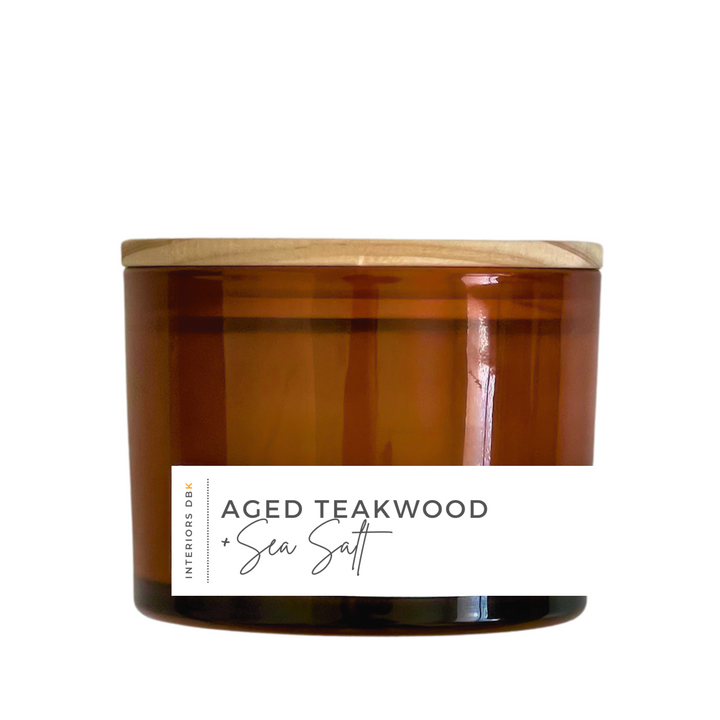 A large Aged Teakwood & Sea Salt soy candle in an amber glass vessel with a natural wood lid, featuring a 12 oz volume and a sophisticated, sustainable design