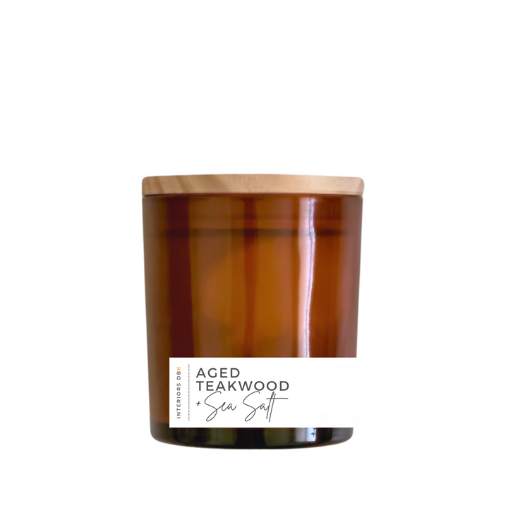 A small Aged Teakwood & Sea Salt soy candle in an amber glass vessel with a natural wood lid, highlighting its 5.4 oz volume and eco-friendly design.