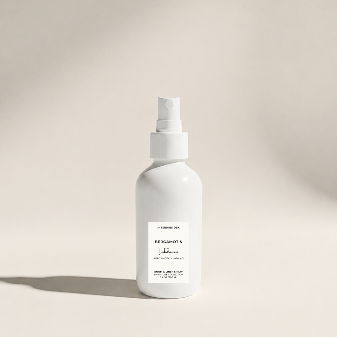 A room and linen spray by Interiors DBK in white glass bottle, labeled Bergamot & Labdanum, a luxury home fragrance.