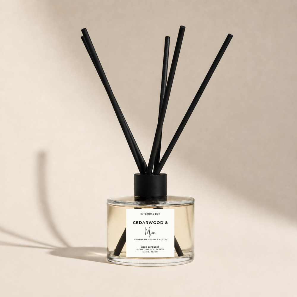 Cedarwood and moss reed diffuser with a clear glass bottle, diffuser oil, and black fiber reeds, set against a warm beige background with a soft shadow.