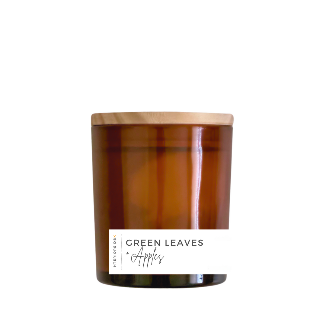 A small Green Leaves & Apples soy candle in an amber glass vessel with a natural wood lid, highlighting its 5.4 oz volume and eco-friendly design.