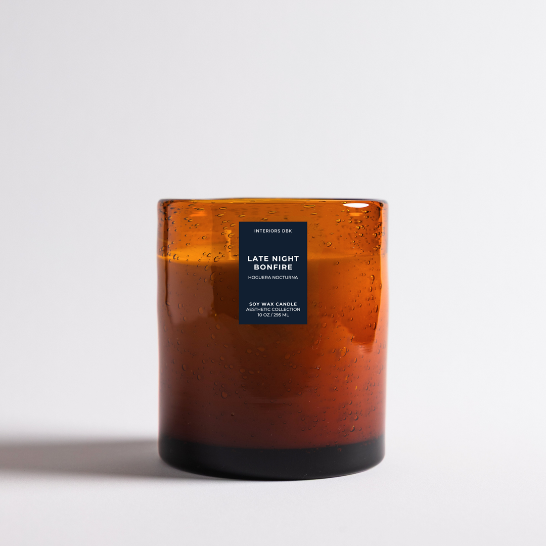 Late Night Bonfire soy wax candle designed in an amber glass jar candle by Interiors DBK photographed on a clean white background.