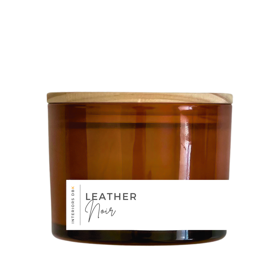 A large Leather Noir soy candle in an amber glass vessel with a natural wood lid, featuring a 12 oz volume and a sophisticated, masculine design.