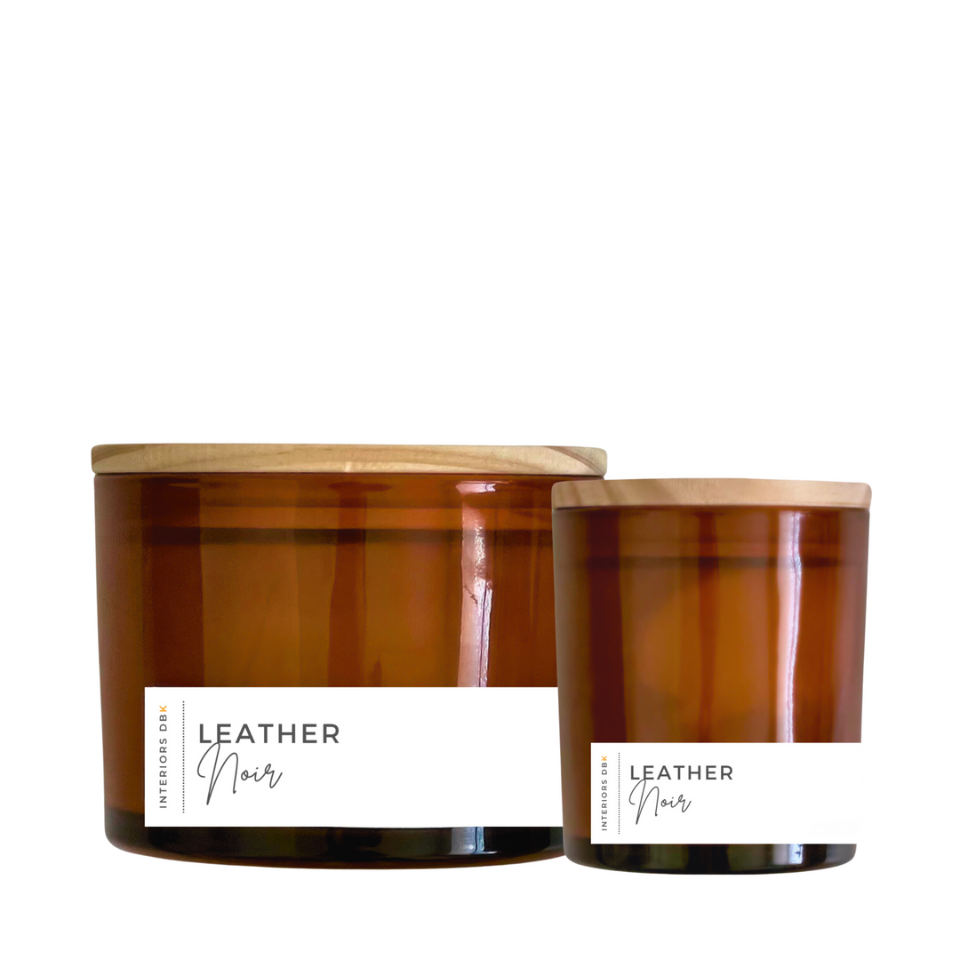 A set of Leather Noir soy candles in amber glass vessels, featuring a small and large candle with natural wood lids, showcasing the bold and masculine design.