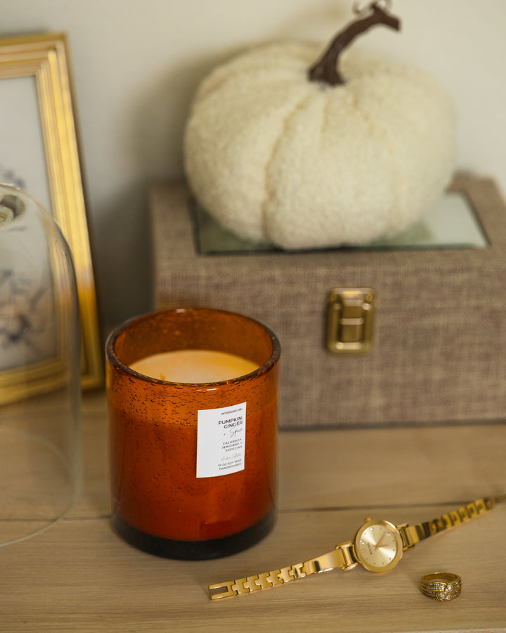 Luxury soy candle with warm pumpkin, spice, and citrus blend in amber glass vessel perfect for the fall season.