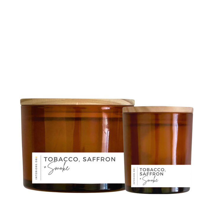 A set of Tobacco, Saffron and Smoke soy candles in amber glass vessels, featuring a small and large candle with natural wood lids, showcasing the warm and smoky design.